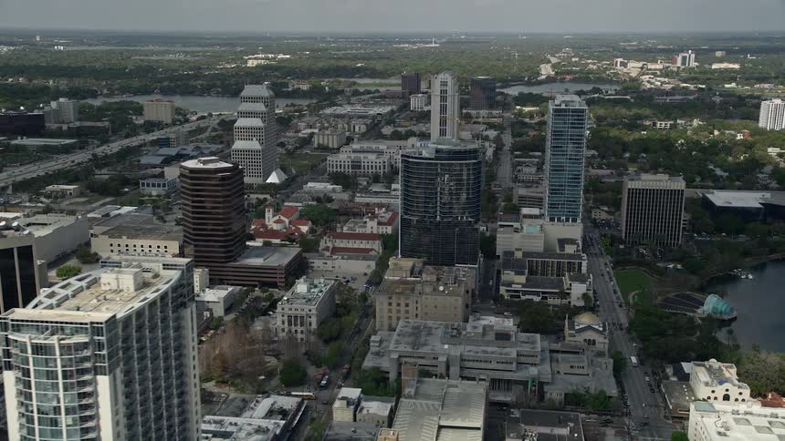 An aerial flyby of high-rise skyscrapers and office buildings in downtown Orlando Florida on a partly cloudy day