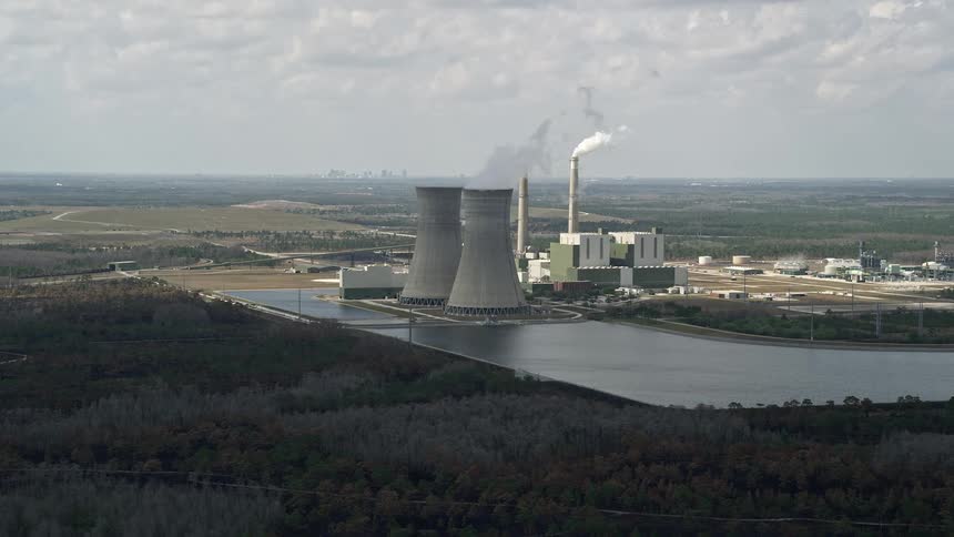 A stunning aerial view of a coal-fired power plant in central Florida generating energy with smoke billowing out of the stacks on a partly cloudy day