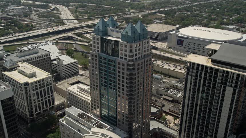 Approaching the SunTrust Center this aerial footage showcases a bustling downtown Orlando with its high rise buildings busy highways and heavy traffic