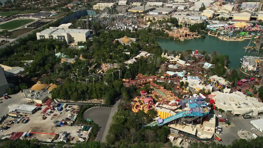 A breathtaking aerial view of Universal Studios theme park rides in Orlando Florida captured during the spring or summer season amidst partly cloudy skies