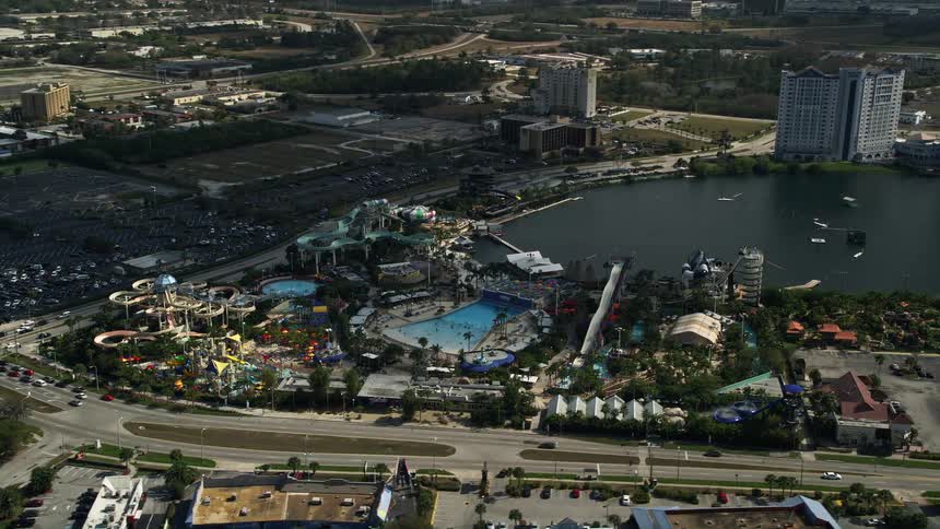 Aerial footage of Wet n Wild water park in Orlando Florida orbiting over water slides and attractions on a partly cloudy day