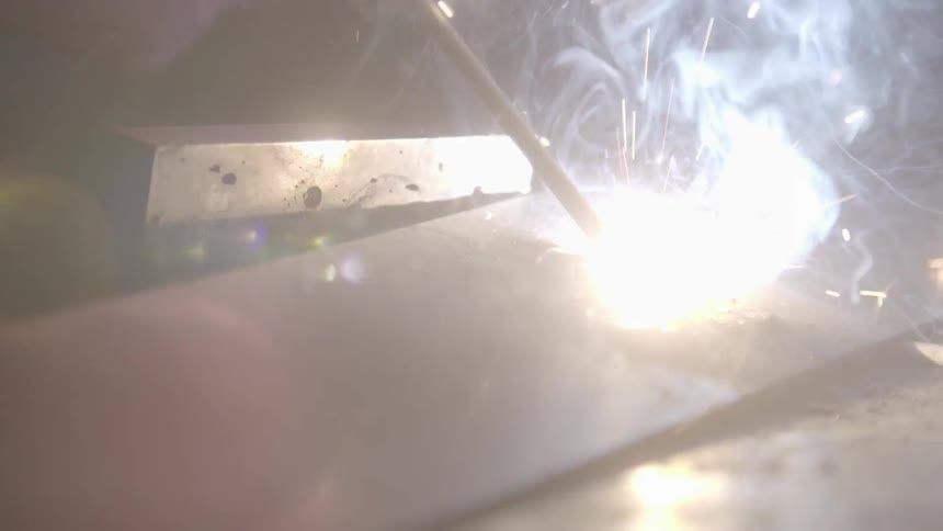 A person is welding metal giving off sparks