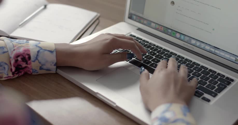 A woman types on a laptop keyboard