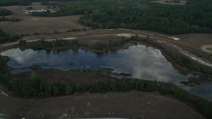 Approaching a small lake in Clermont Florida with partly cloudy skies and lush greenery surrounding the shoreline in the summertime