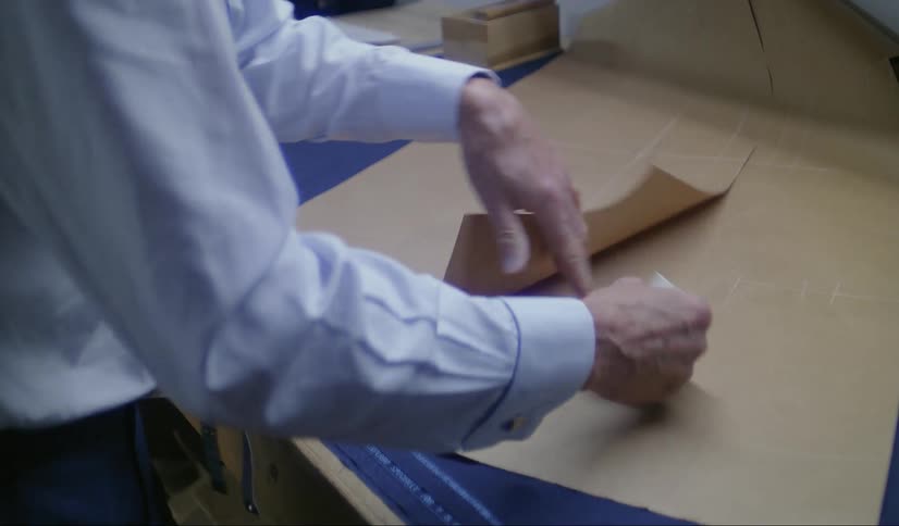 A man using a paper cutter to cut out a shape on a cardboard paper on a table