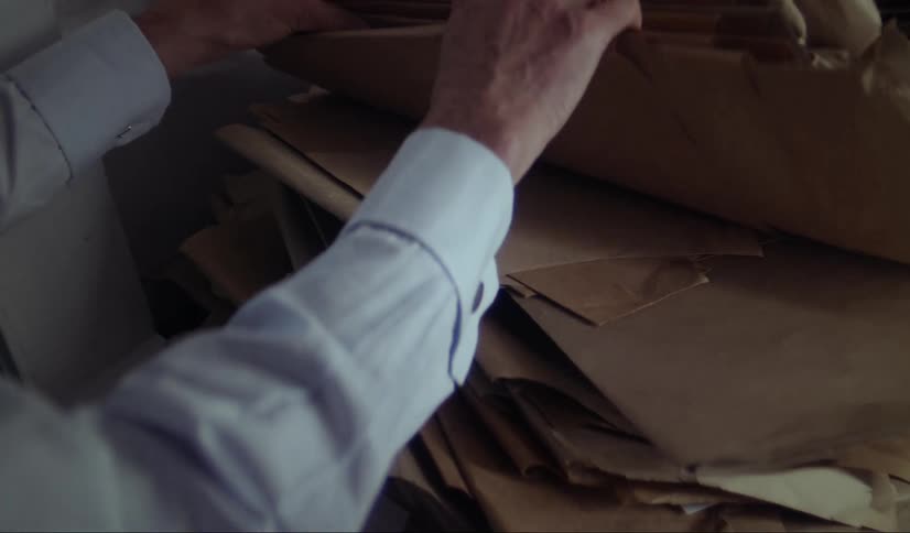 Man sorting through brown pattern paper looking for something