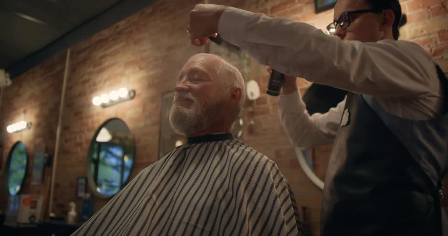 Barber combs the hair of a client sitting on the barber shop chair