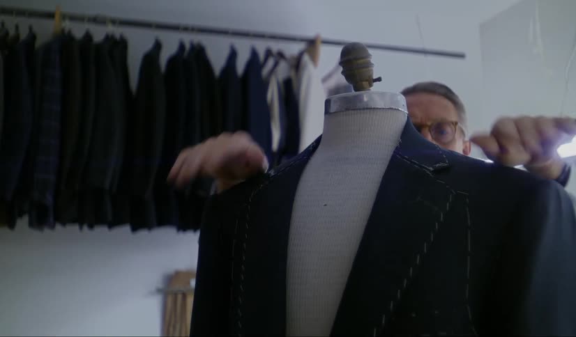 A tailor adjust the collar of a suit coat that he is currently preparing