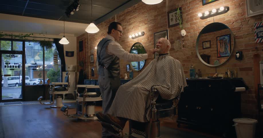 Barber combs the beard of a client sitting on the barber shop chair