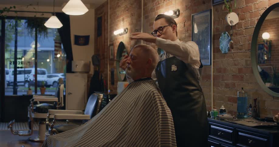 Barber combs the hair of a client sitting on the barber shop chair