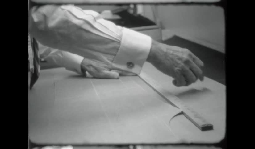 Tailor marks pattern using a wooden ruler and chalk
