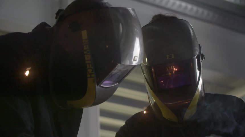 Two welders working and sparks flying in the air