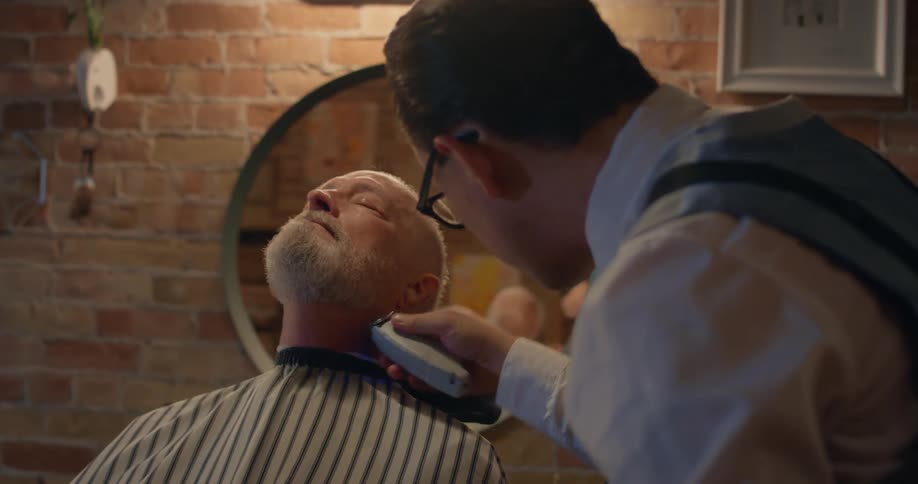 Hairdresser trims the beard of a customer sitting on the barber shop chair