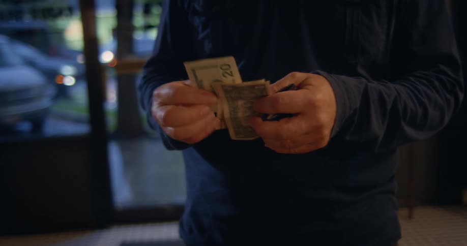 Man standing in car rental shop sorting cash bills in his hands daytime