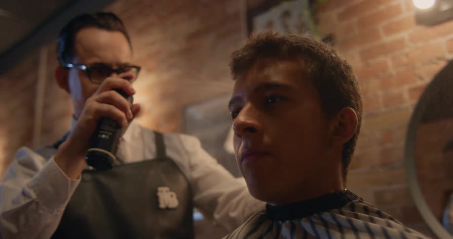 The view is of a young teenager at a barber shop getting his hair cut