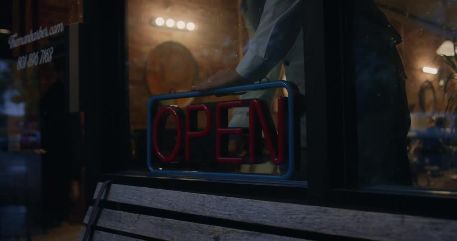 Owner of a barber shop turns off the open neon sign on the front of the store