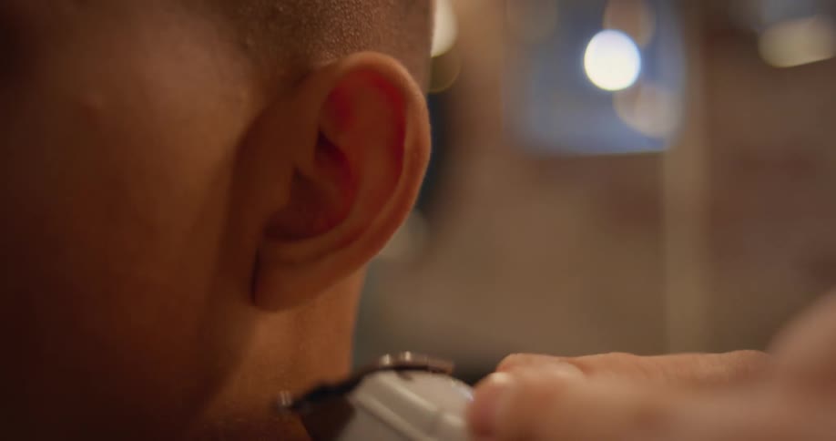 A close up of a barber using clippers on a customers neck and head