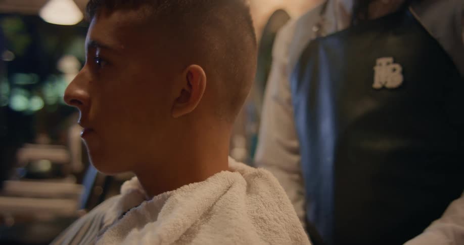 A barber places a wet towel around a clients neck
