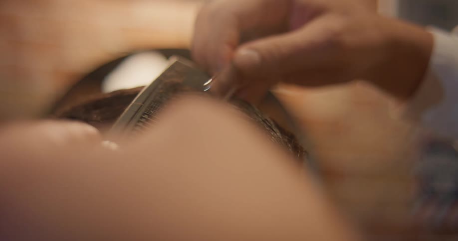 Close up of a barber combing and cutting a mans hair in the barber shop