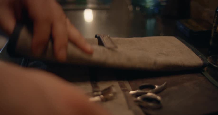A person placing a cloth fold on a counter opening it and taking scissors out