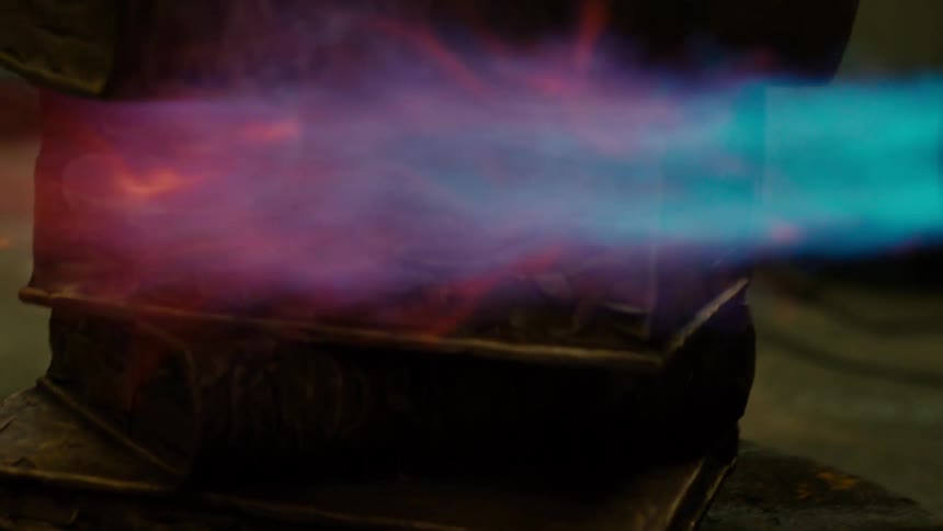A close up of a torch flame on a stack of steel books as they are being rotated around on a platform