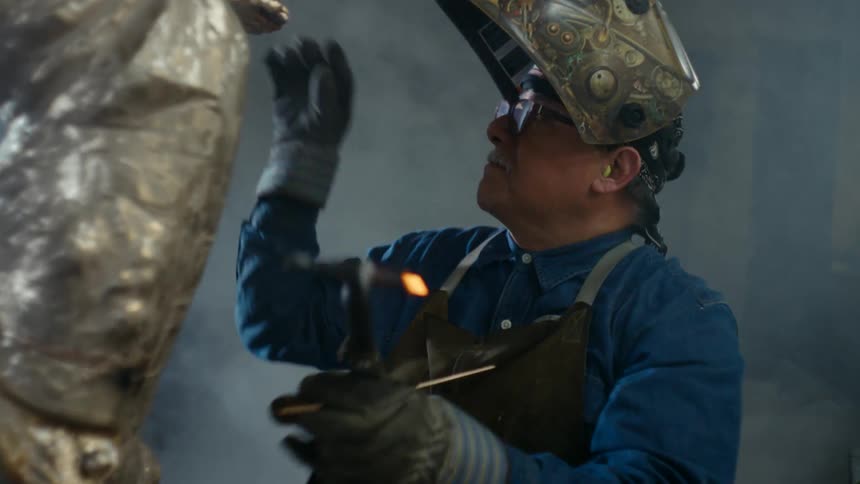 Close up of a welder welding a large metal statue in his workshop