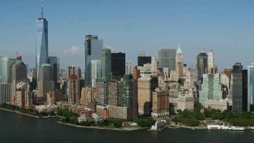 An aerial midday shot of the tower block of a dense metropolis along the riverfront