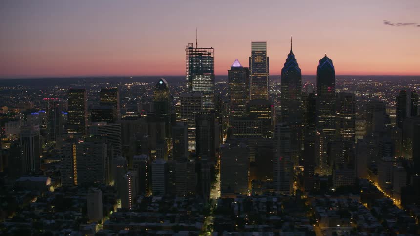 Aerial view of illuminated skyscrapers and high rise buildings in the city at dusk