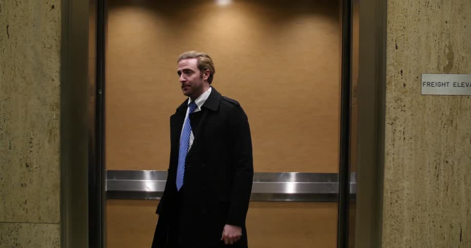A man walks into an elevator and pushes a button