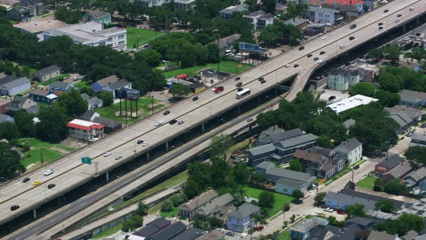 A modern overhead bridge surrounded by numerous houses and lush green trees