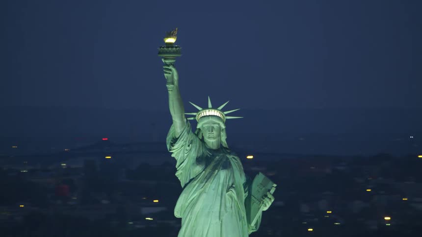 The statue of liberty is lit up at night