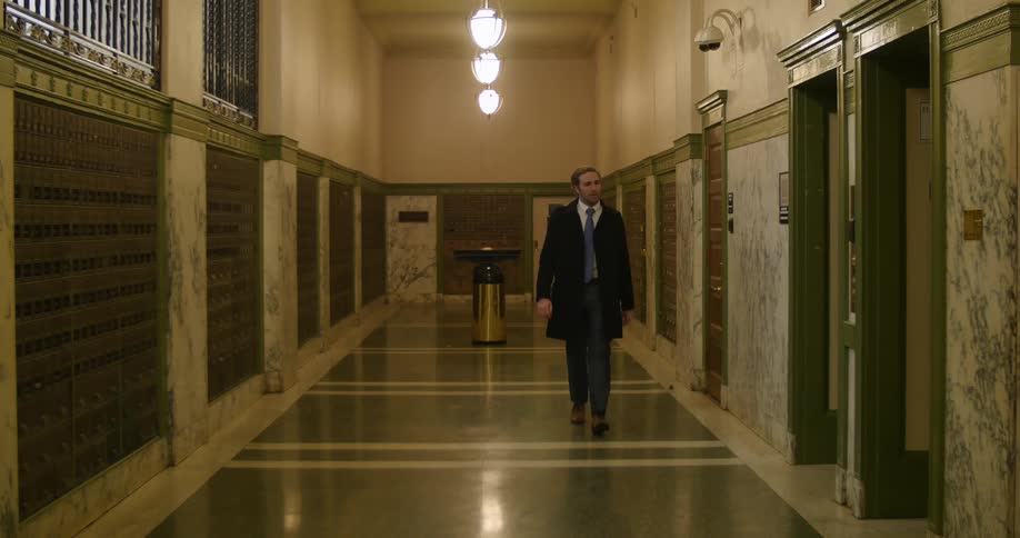 Well-dressed man walking in a hallway and pushing the elevator button