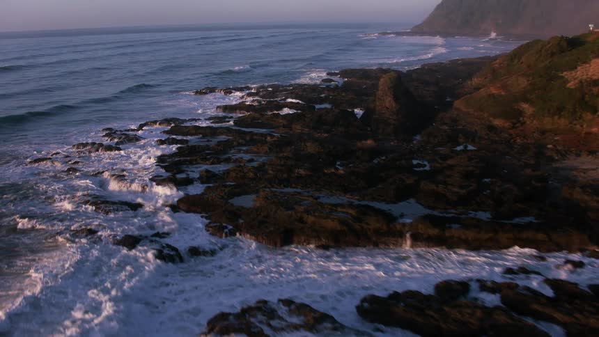 Waves crash onto rocks below a cliff