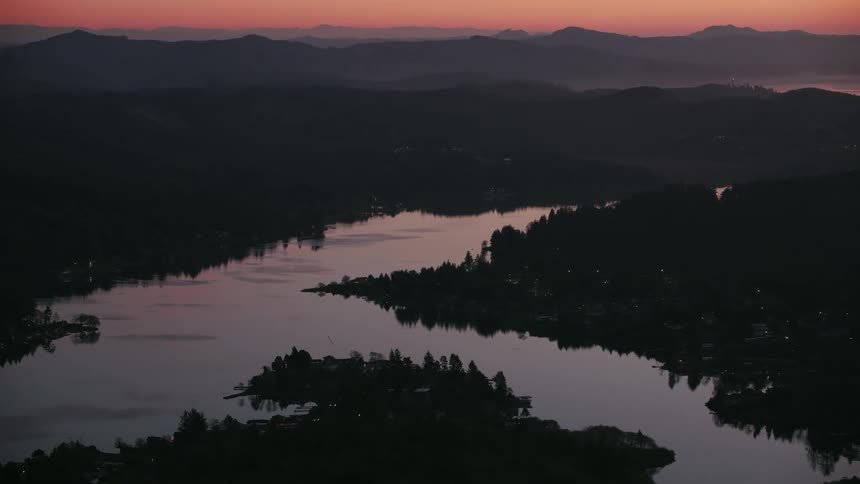 Aerial view of a river on the hills under the evening haze next to the ocean