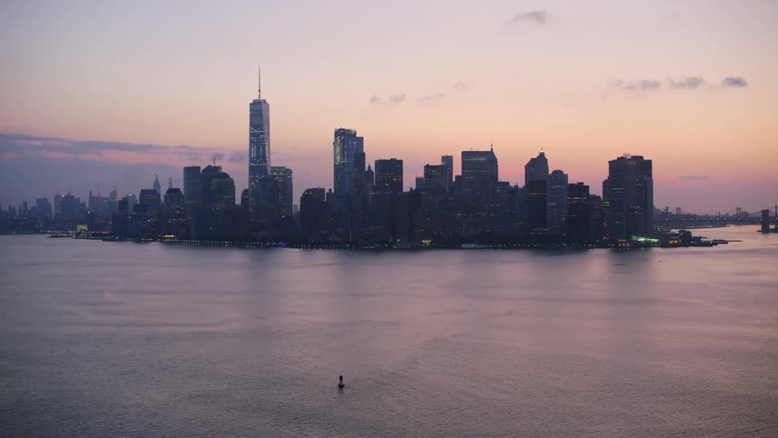 A boat sails away from downtown at dusk