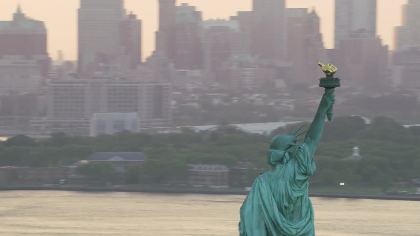 The statue of liberty sits across the sea from downtown