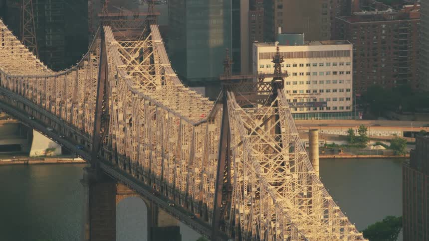 A large suspension bridge crosses a river near a large city