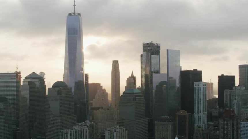 An aerial of a city skyline with tall buildings with unique skyscrapers against a cloudy sky