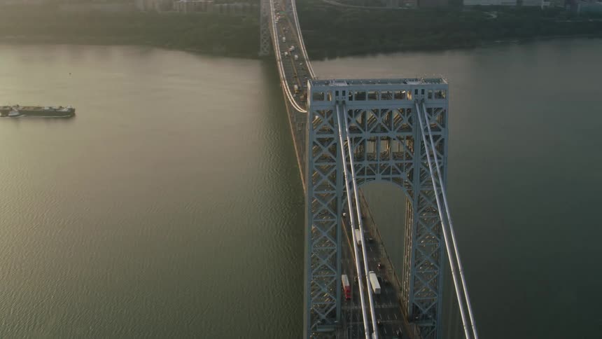 An aerial shot of a suspension bridge with lots of cars headed toward a nearby city