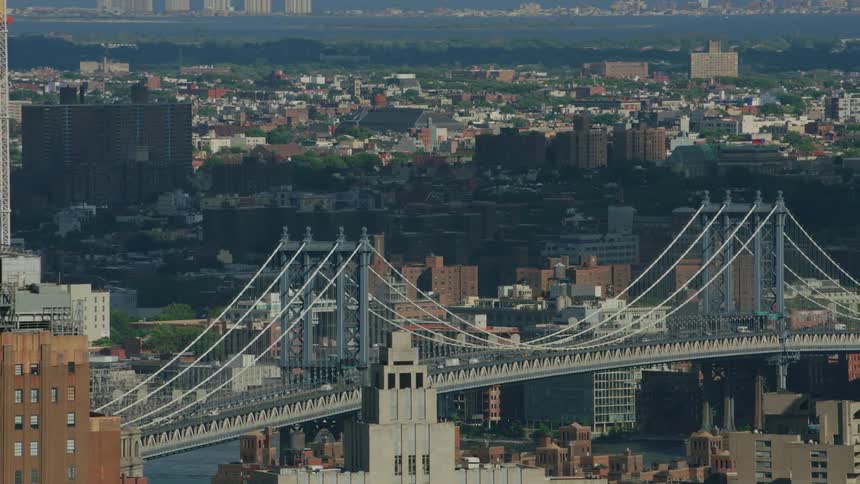 An aerial shot of a bridge over a river in the middle of a big city