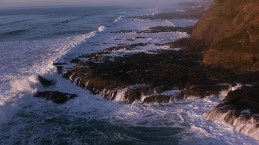 Waves crash onto rocks below a promontory