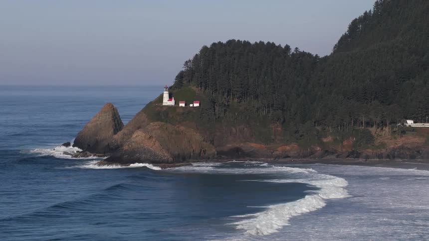 Aerial view of a lighthouse on the mountains close to the ocean