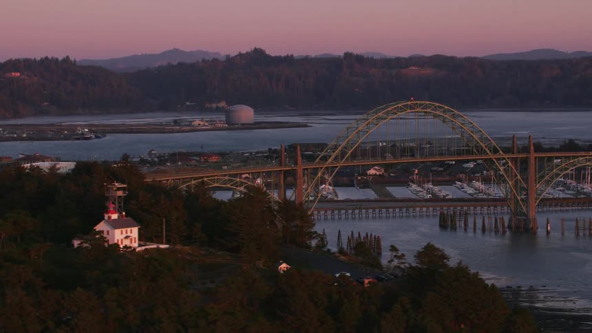 Aerial orbiting view of an arch bridge over a bridge at evening