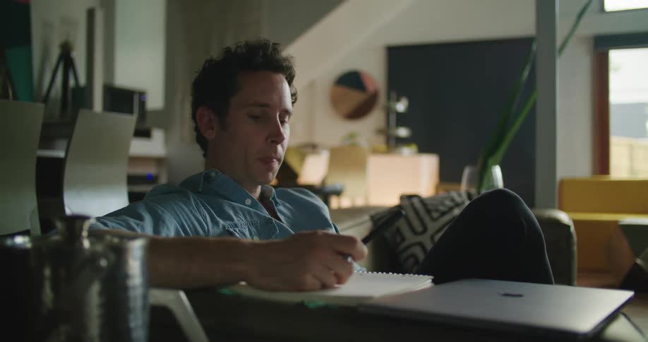 Tired man man finishes working at home closing a laptop and standing up from the couch
