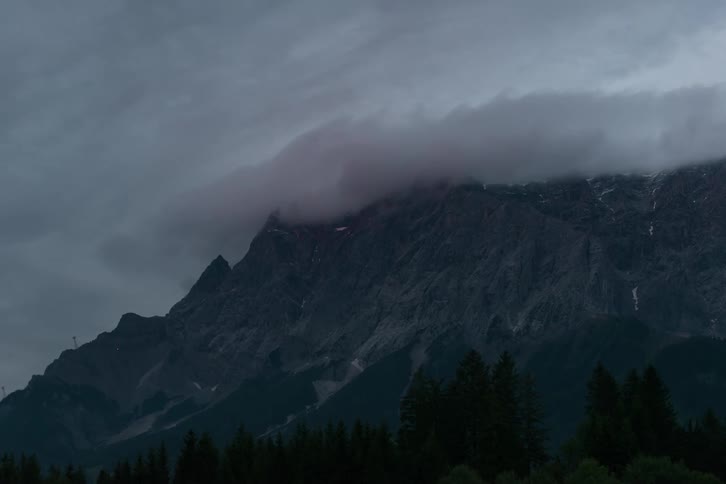The sun is setting and clouds are moving on the Wetterstein mountain range.