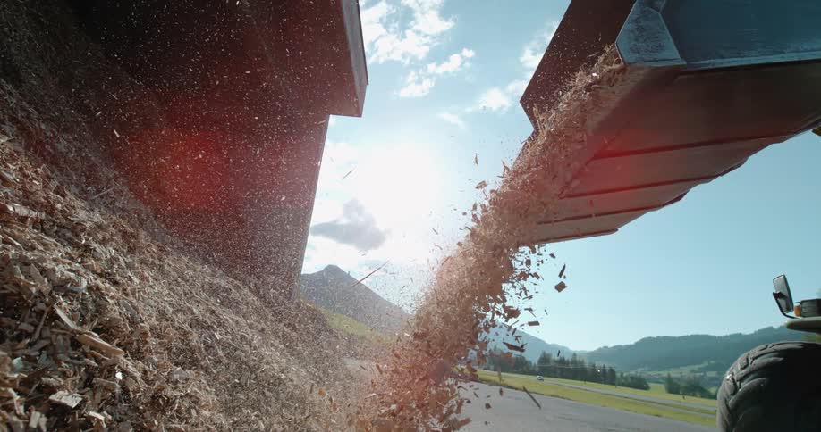 A bulldozer pours mulch onto a pile