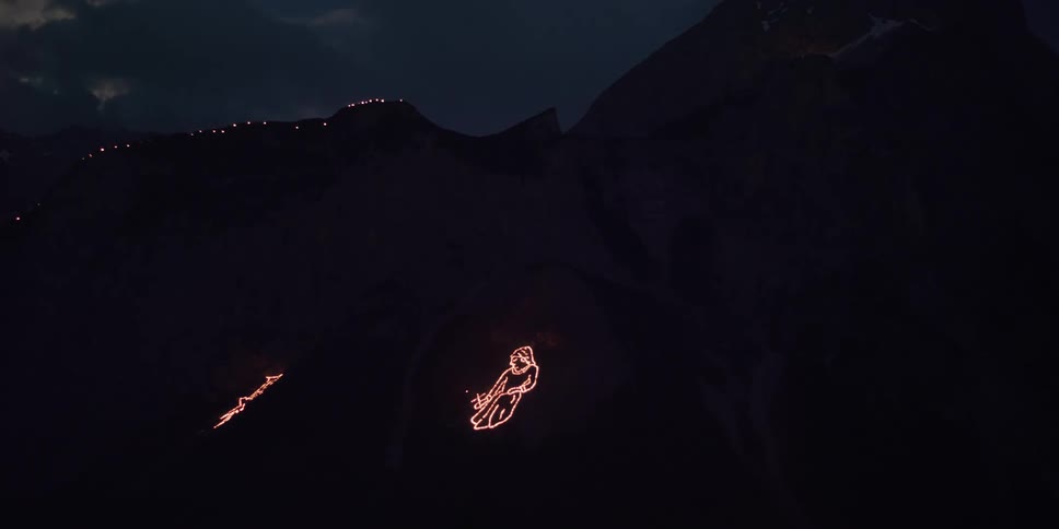 Glowing lights form a pattern on the side of a mountain