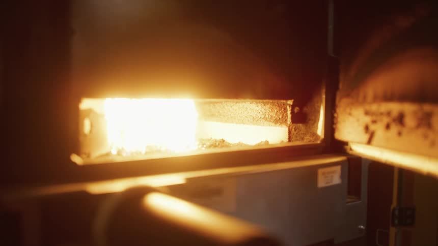 A bright fire is blazing inside a furnace and glowing in the darkness