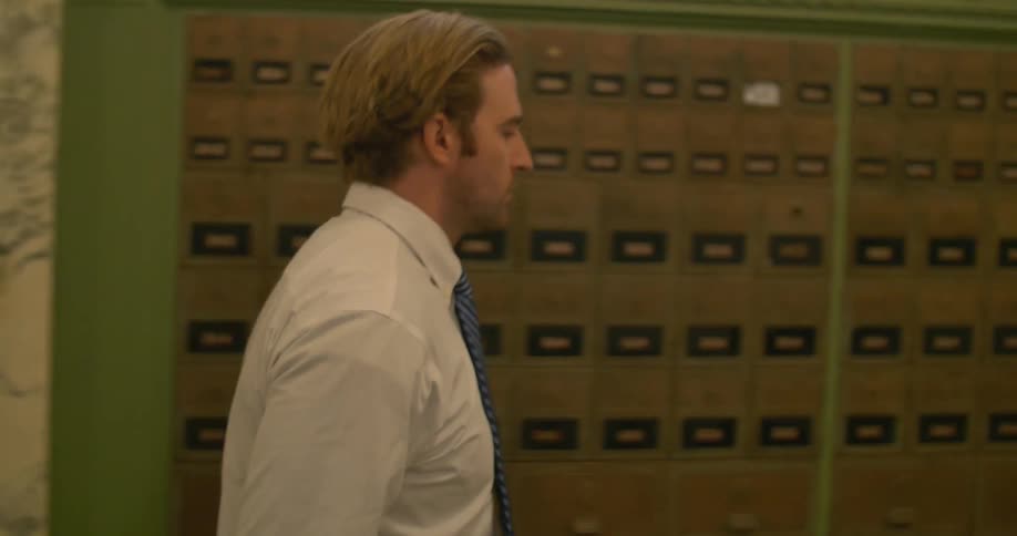 A man wearing a tie walks past lock boxes