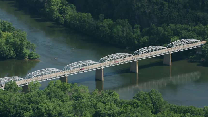 An aerial view of a bridge over a river connecting two forests